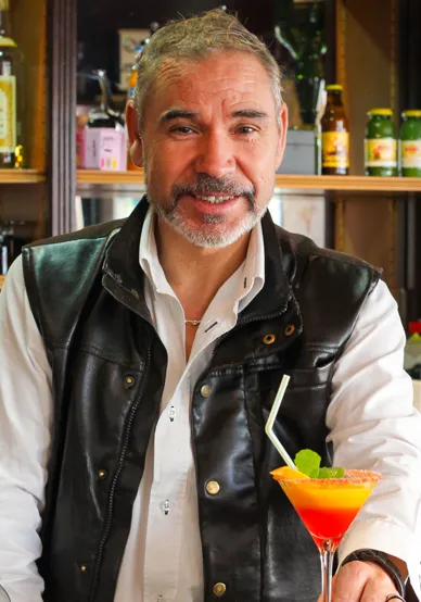 Photo du patron derrière son bar servant un cocktail